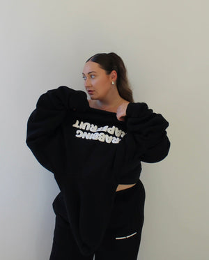 Woman wearing a black oversized sweatshirt with "GRABBING GRAPEFRUIT" on a plain background